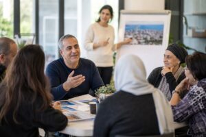 גבר בן 40 משתתף בסדנה במרכז קהילתי על נקודות זיכוי יישוב מוטב.
